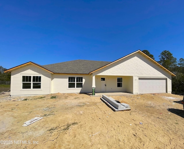 back of house featuring a shingled roof and an attached garage