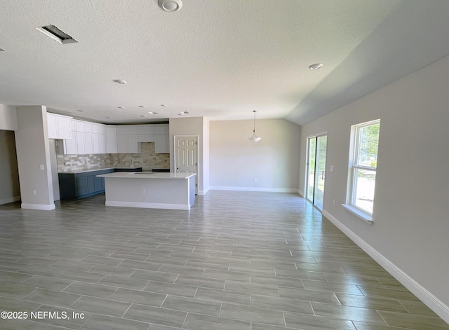 unfurnished living room with baseboards, lofted ceiling, and a textured ceiling