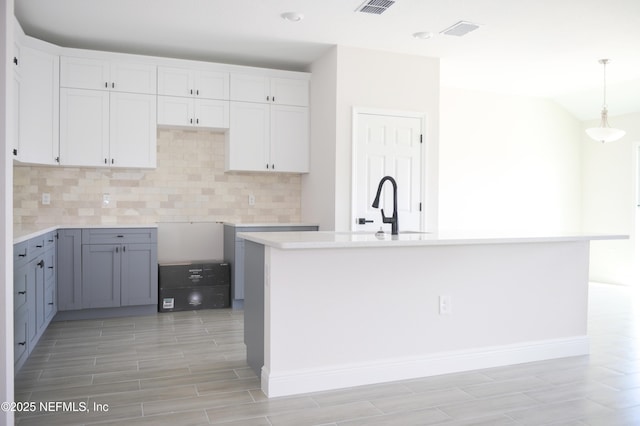 16521 SW 31st Ter, Ocala, FL 34473 - kitchen with a sink, decorative backsplash, white cabinetry, wood tiled floors, and pendant lighting