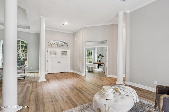 entryway featuring french doors, crown molding, ornate columns, and hardwood / wood-style floors