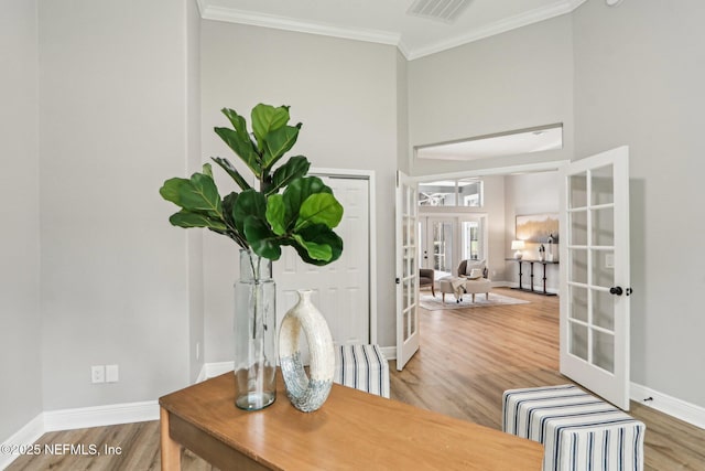 foyer with wood-type flooring, ornamental molding, and french doors