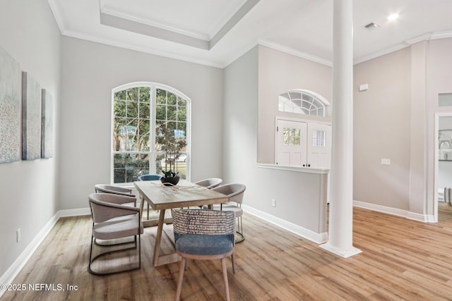 dining area with light hardwood / wood-style flooring, crown molding, and a raised ceiling