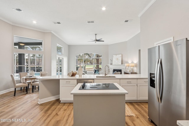 kitchen with sink, white cabinetry, stainless steel fridge, and a center island