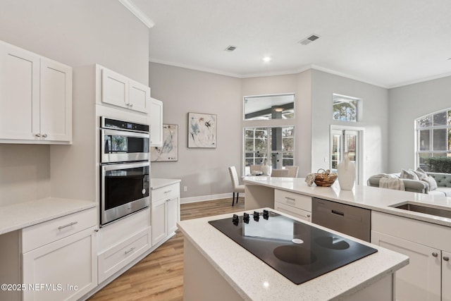 kitchen featuring light hardwood / wood-style floors, stainless steel appliances, french doors, a kitchen island, and white cabinets