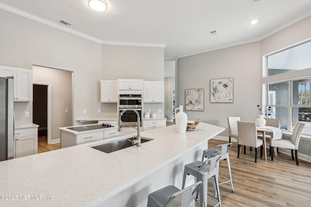 kitchen featuring sink, crown molding, appliances with stainless steel finishes, a breakfast bar area, and white cabinets