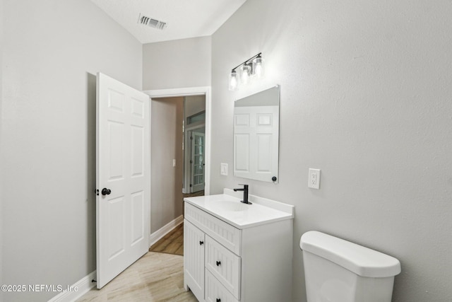 bathroom with wood-type flooring, toilet, and vanity