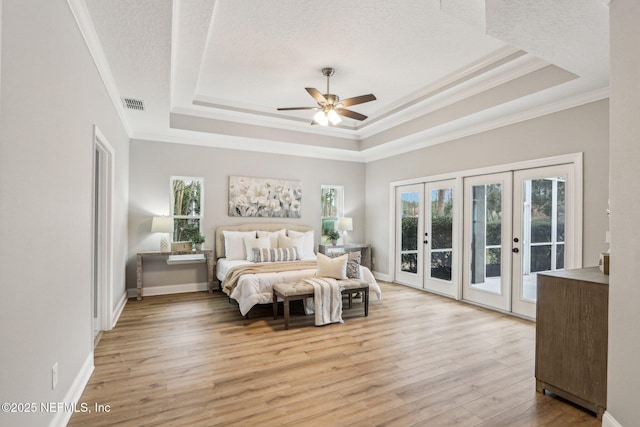 bedroom with ceiling fan, access to exterior, a raised ceiling, multiple windows, and french doors