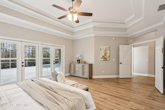 bedroom featuring ceiling fan, a tray ceiling, access to outside, wood-type flooring, and french doors