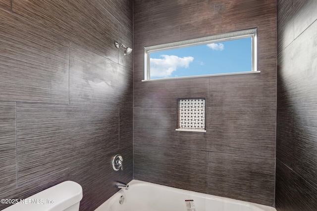 bathroom with toilet and tiled shower / bath