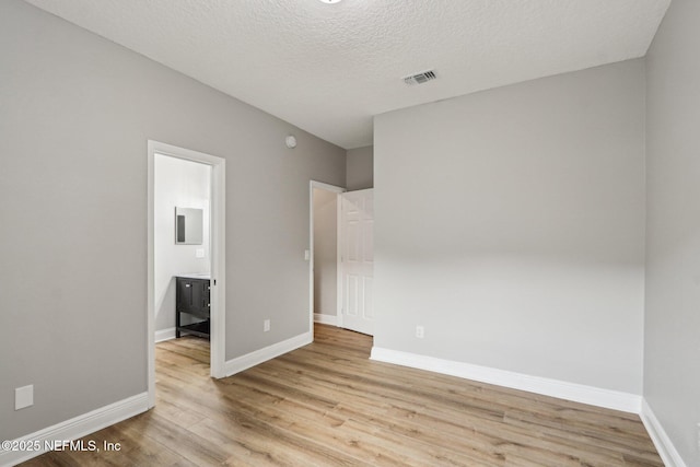 empty room featuring light wood-type flooring and a textured ceiling