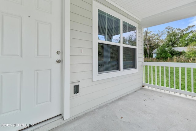 doorway to property featuring a lawn and covered porch