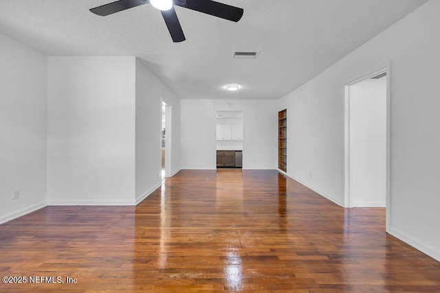 unfurnished living room with ceiling fan, dark hardwood / wood-style flooring, built in features, and a textured ceiling