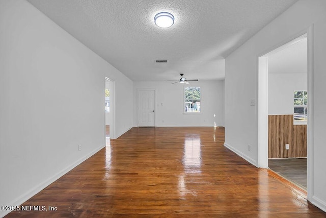 unfurnished living room featuring dark hardwood / wood-style flooring, ceiling fan, wood walls, and a textured ceiling