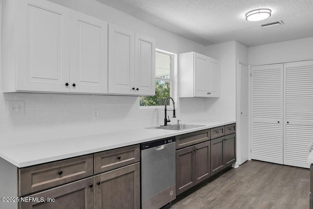 kitchen with dishwasher, sink, light hardwood / wood-style flooring, a textured ceiling, and tasteful backsplash