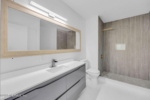 bathroom featuring tile patterned flooring, a tile shower, vanity, and toilet