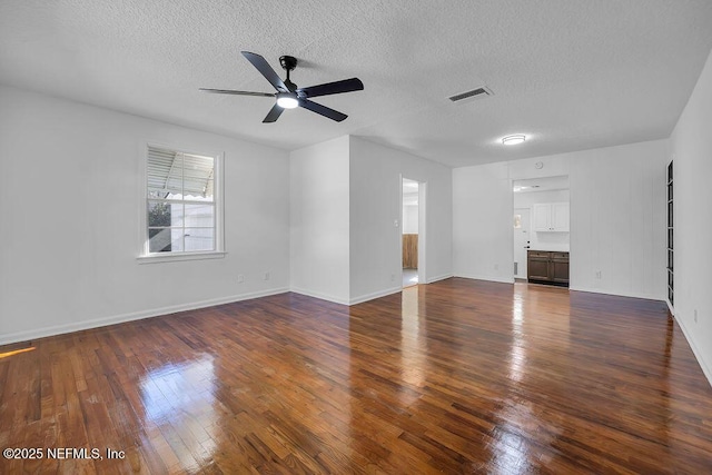 unfurnished living room featuring dark hardwood / wood-style floors, ceiling fan, and a textured ceiling