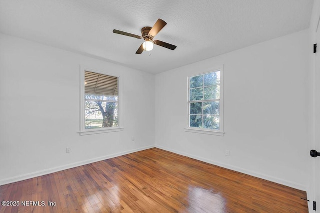 spare room with wood-type flooring, a textured ceiling, ceiling fan, and a healthy amount of sunlight