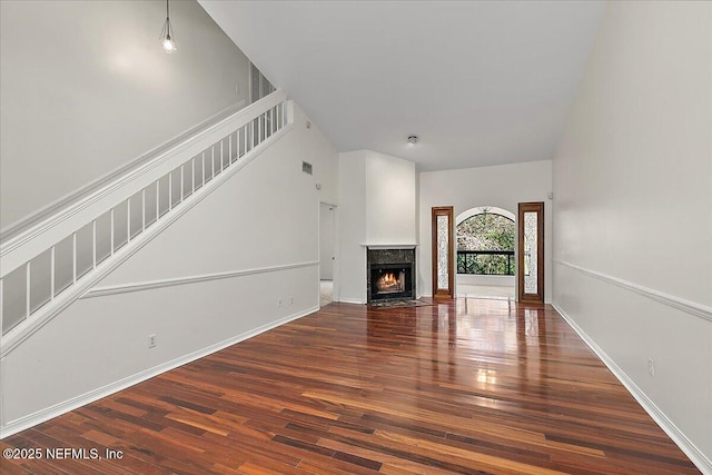 unfurnished living room featuring a premium fireplace and dark hardwood / wood-style floors