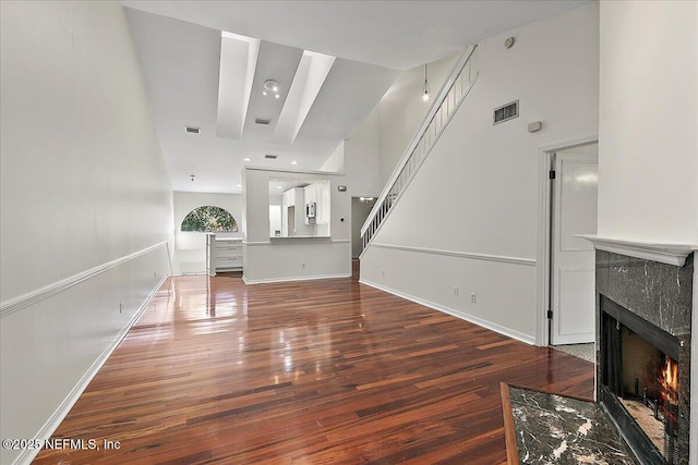 unfurnished living room featuring dark wood-type flooring and a high end fireplace