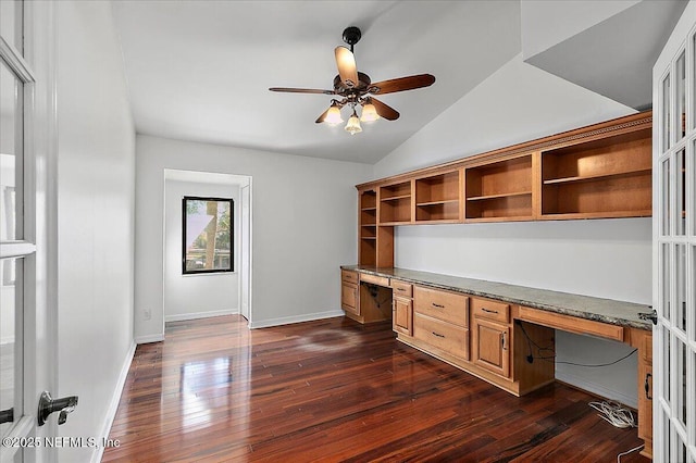 unfurnished office with ceiling fan, dark hardwood / wood-style flooring, built in desk, and vaulted ceiling