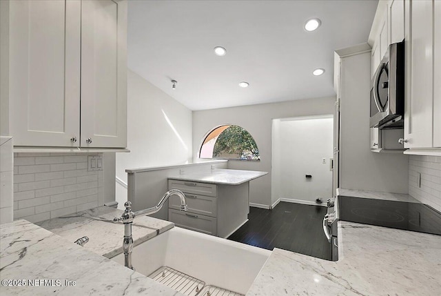 kitchen with white cabinets, decorative backsplash, and light stone counters