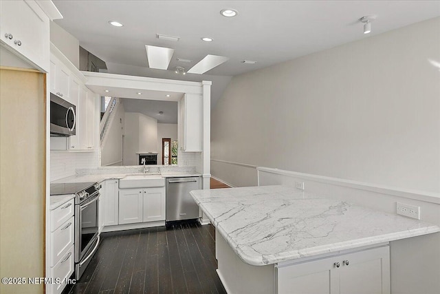 kitchen with kitchen peninsula, white cabinetry, and stainless steel appliances