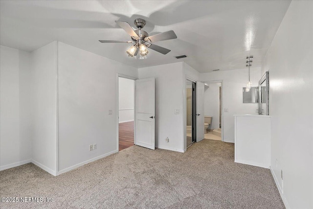 unfurnished bedroom featuring ceiling fan, carpet floors, and ensuite bath