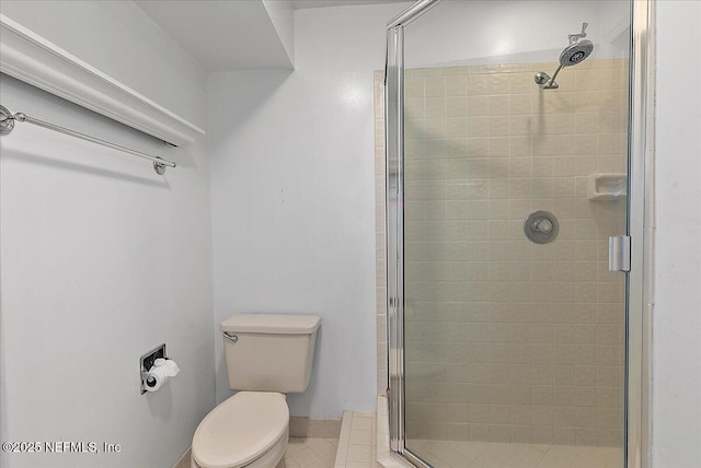 bathroom featuring tile patterned floors, toilet, and a shower with shower door