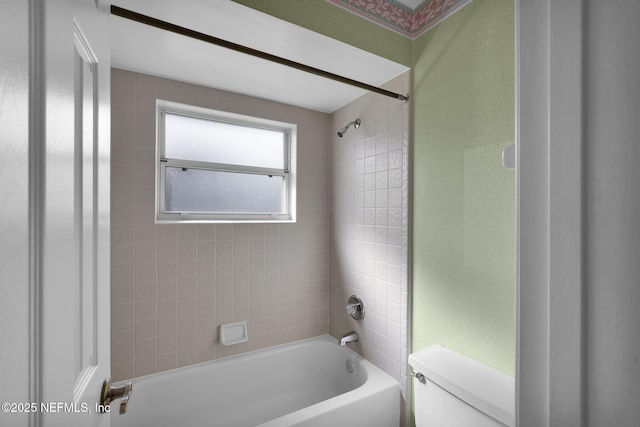 bathroom featuring toilet and tiled shower / bath