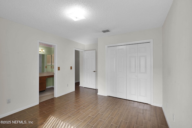 unfurnished bedroom featuring a textured ceiling, connected bathroom, and a closet