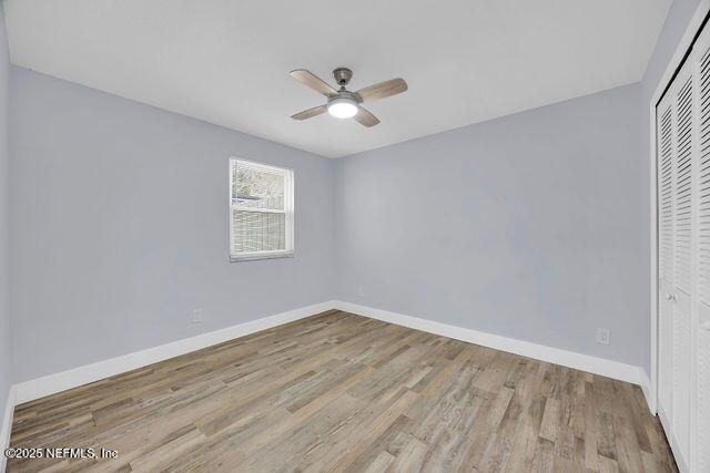 unfurnished bedroom featuring ceiling fan, light hardwood / wood-style floors, and a closet