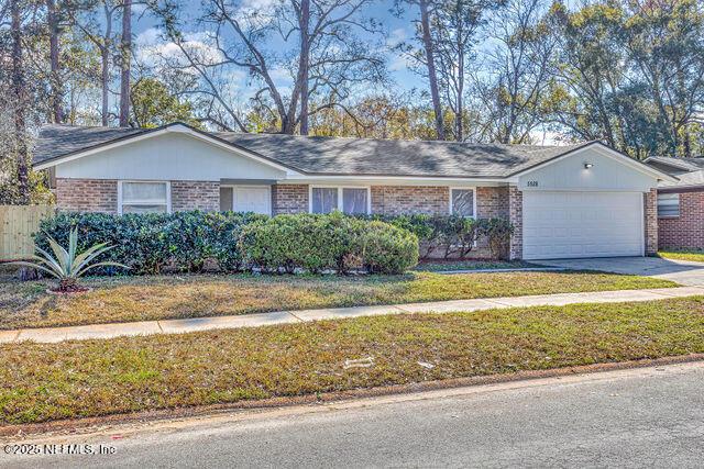 ranch-style home featuring a garage and a front lawn