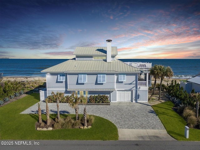 view of front of home with a lawn, an AC wall unit, a garage, and a water view