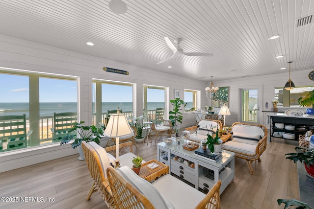 sunroom / solarium with a water view and ceiling fan with notable chandelier