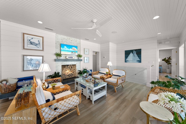 living room featuring wooden ceiling, wood-type flooring, ceiling fan, wooden walls, and a fireplace