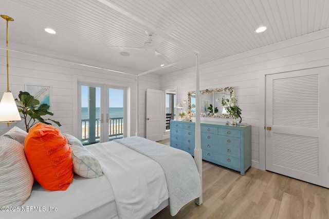 bedroom with a water view, ceiling fan, french doors, access to exterior, and light hardwood / wood-style flooring