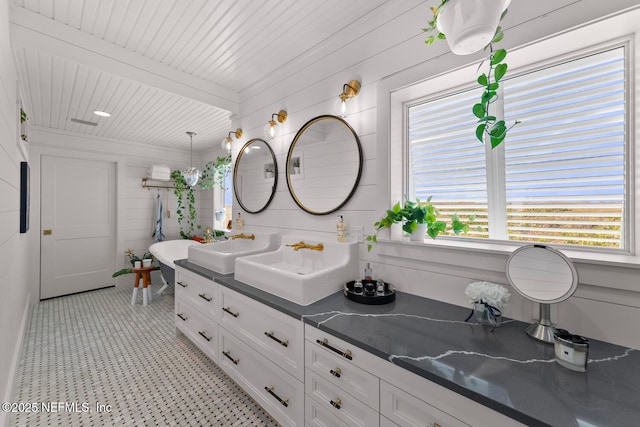 bathroom featuring beam ceiling, wood walls, and vanity