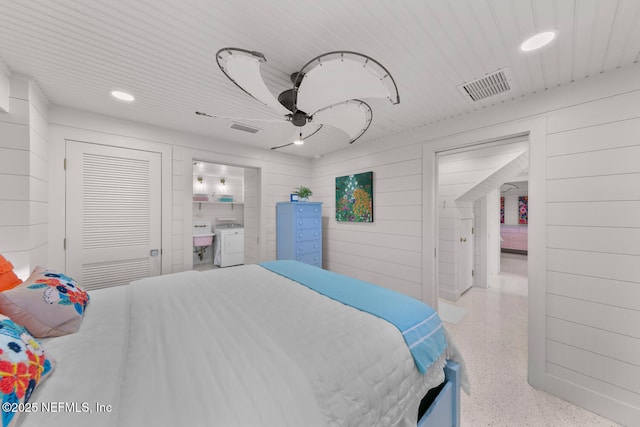 bedroom featuring a closet, washer / clothes dryer, and wood walls