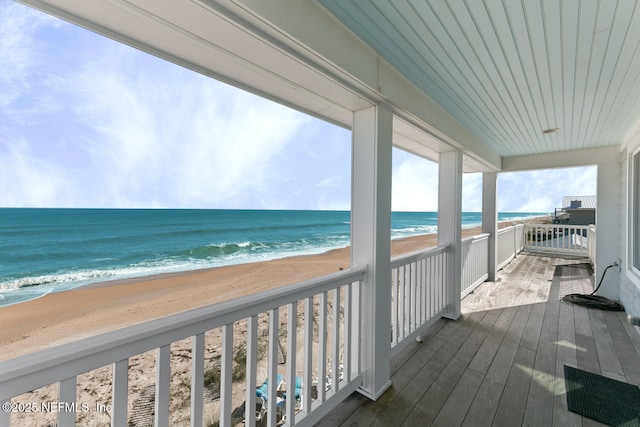 balcony with a water view and a view of the beach