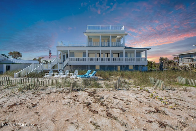 back house at dusk with a balcony and a porch