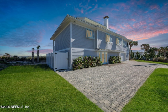 property exterior at dusk with a garage and a lawn