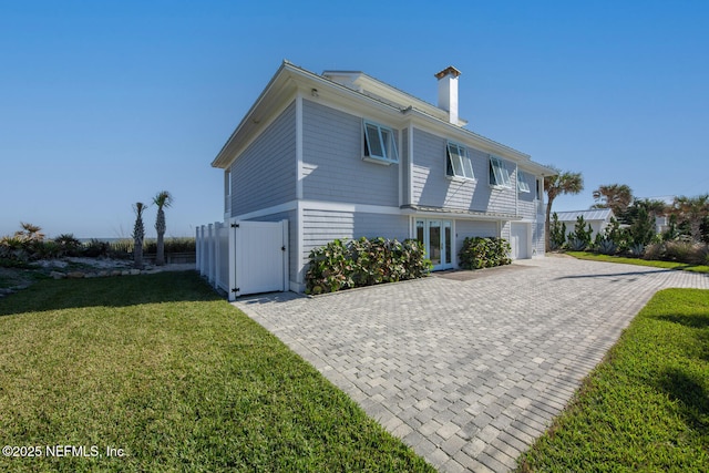 view of home's exterior featuring french doors, a yard, and a garage