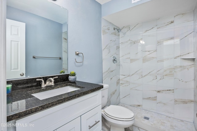 bathroom featuring vanity, toilet, and a tile shower