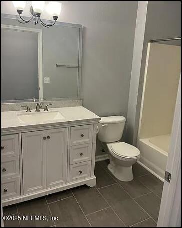 full bathroom with a notable chandelier, tile patterned floors, toilet, shower / washtub combination, and vanity