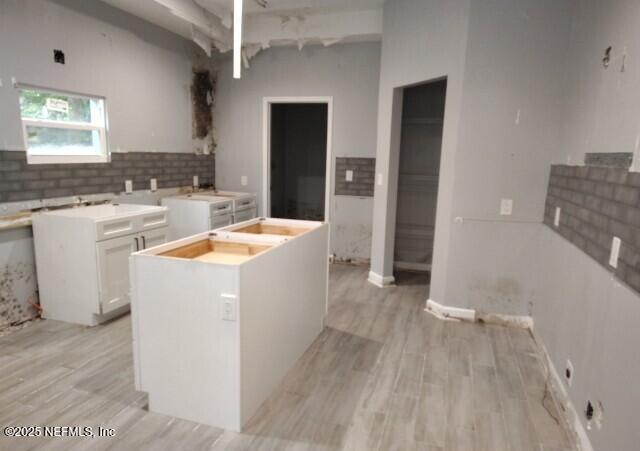 kitchen featuring white cabinets, a kitchen island, and light wood-type flooring