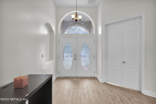 entryway featuring a notable chandelier, light hardwood / wood-style flooring, a high ceiling, and french doors