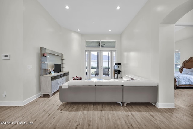 living room featuring light wood-type flooring, a towering ceiling, and french doors