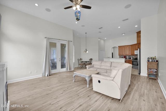 living room featuring french doors, light wood-type flooring, and ceiling fan