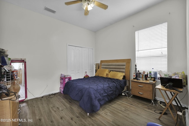 bedroom featuring multiple windows, ceiling fan, a closet, and dark wood-type flooring