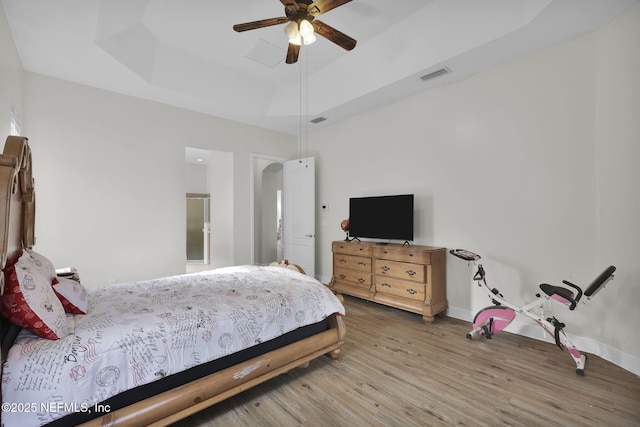 bedroom featuring a raised ceiling, ceiling fan, and hardwood / wood-style floors